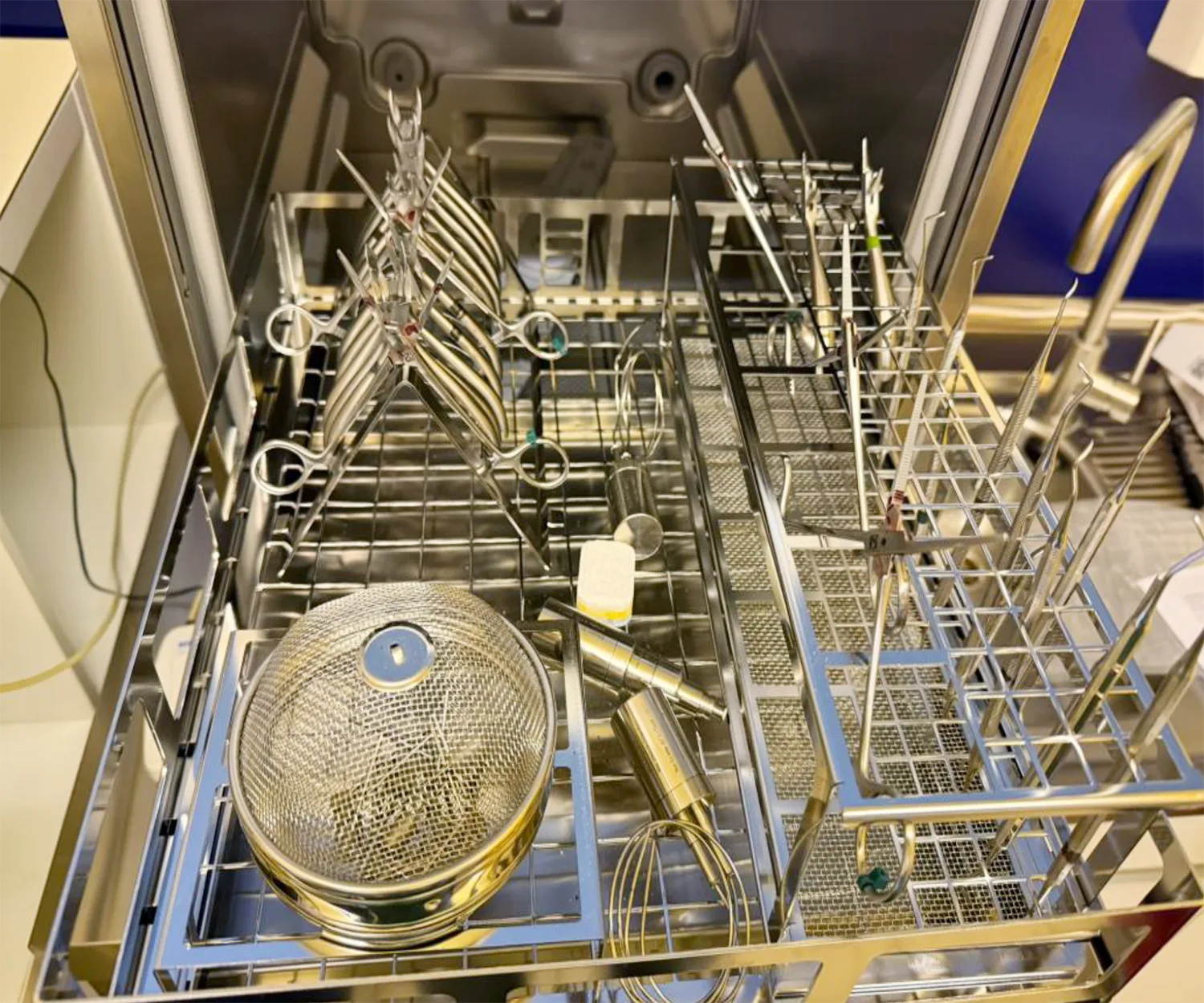 Beladener Instrumentenkorb in einer Reinigungs und Desinfektionsanlage mit aufgestellten Hohlkörperinstrumenten und Siebbehälter